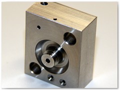Heat treated stainless steel hydraulic valve end cap with internal circuitry precision deburred under 45x magnification.